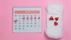 Directly Above Shot Of Sanitary Pad By Calendar Over Pink Background