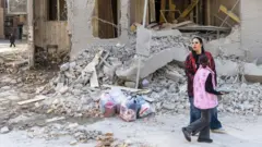 Mujer camina por los escombros de un edificio en Teherán