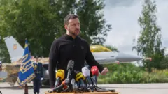 O presidente da Ucrânia, Voldymyr Zelensky, discursandosuperboss casinofrente a um dos caças F-16 que a Ucrânia recebeusuperboss casinojulho.