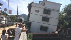 Residents look at subsided and leaned buildings at Ziyuan County on August 3, 2015 in Guilin,