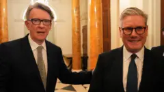 白い壁に白黒のタイル貼りの床、オレンジ色の大理石の柱が並ぶ広い廊下に、ダークスーツ姿で並ぶ両氏