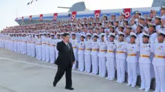 O líder norte-coreano Kim Jong-un em revista a uma tropa de marinheiros, em frente a um navio