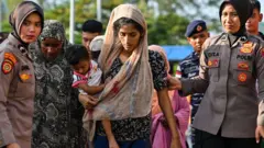 Pengungsi Rohingya menaiki kapal feri di sebuah pantai di pulau Sabang, provinsi Aceh, Indonesia pada 22 November 2023, saat mereka direlokasi oleh aparat keamanan.