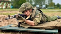 Белорусский солдат лежит на деревянном настиле с автоматом и целится