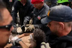 Un miembro de un equipo de rescate de EE.UU. ayuda a una persona que había quedado atrapada bajo los escombros de un edificio tras los terremotos que azotaron el país, en La Guaira.