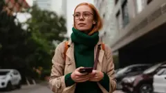 Seorang perempuan memegang telepon genggam.