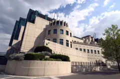 Prédio grande de concreto com janelas verdes e grades