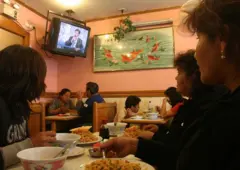 Un grupo de personas come bajo una TV en un restaurante de Lima.