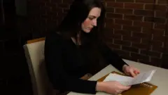 Michele olhando para papéis em cima da mesa