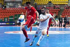 بازیکن تیم فوتسال ایران با لباس سفید و بازیکن افغانستان با لباس سرخ در میدان فوتسال