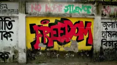 Mural painted on a wall reads "FREEDOM" in bright red letters, on a yellow background. Above that text are the words "No more silence".