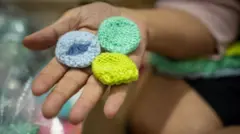 Foto de 3 minúsculos gorros de tricô na palma de uma mão.