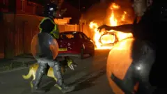 Policial passa com cãosimulador aposta esportivarua com um carrosimulador aposta esportivachamas ao fundo 