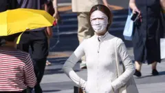 2026年5月30日，中國北京天氣炎熱，一名居民遮住臉部防曬。北京當日錄得2026年首個高溫日，氣溫達攝氏35度。