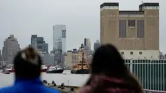 People look on as emergency personnel work at the scene of a helicopter crash on the Hudson River near lower Manhattan in New York, as seen from Newport, New Jersey U.S., April 10, 2025.