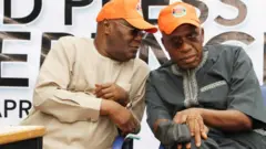 Former Vice President Atiku Abubakar dey tok to Rotimi Amaechi on di right. Two of dem wear orange fez cap