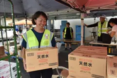 Voluntária sorrindo ao carregar caixa
