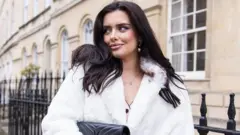 Sadie, mulher de cabelos longos e escuros com casaco branco