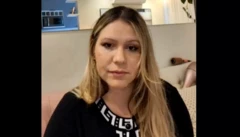 Raquel Cantarelli, uma mulher loira, de cabelos compridos e pele clara, olha para a câmera