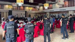 特警隊員包圍了坐在酒店大廳紅色椅子上的信眾。