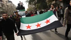 صورة تظهر سوريين يرفعون علم "الثورة السورية في الشارع.