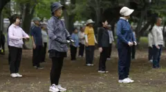 Un grupo de personas mayores realizan ejercicio físico en un parque en la mañana, en Tokio, Japón.