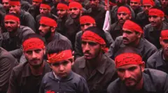 Miembros del Cuerpo de la Guardia Revolucionaria Islámica (CGRI) junto a un niño en una demostración en Teherán durante la guerra de Iran-Irak. 