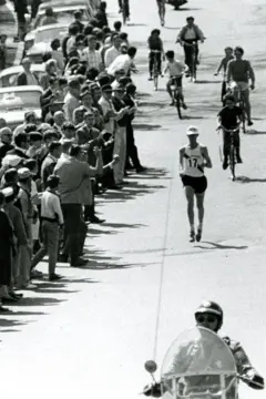 Amby Burfoot disputa a maratona nas ruas de Boston de 1968, acompanhado por ciclistas e escoltado pela polícia