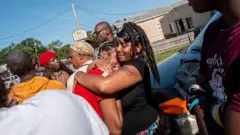 Syrnerica Pugh (à direita) é consolada enquanto lamenta a morte de seus sobrinhos e sobrinhas.