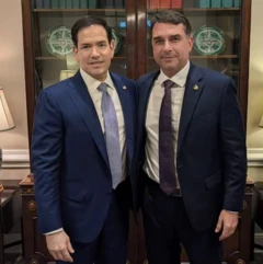 Foto com Marco Rubio (à esquerda) e Flávio Bolsonaro (à direita). Os dois são homens brancos, usando ternos azul-marinho