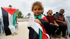 طفلة صغيرة في غزة تحمل العلم الفلسطيني