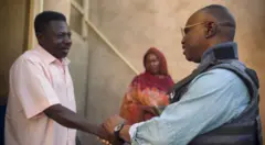 تُظهر الصورة محمد عثمان، مراسل بي بي سي، وهو يصافح أحد جيرانه في مدينته أم درمان التي عاد إليها بعد عامين من الغياب.