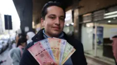 Suriyeli bir adam elinde yeni banknotları tutuyor. Farklı renklerde 10, 25, 50, 100, 200 ve 500 liralık banknotlar gözüküyor.