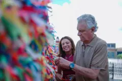 Caiado mexendo em fitinhas do Senhor do Bonfim, com esposa atrás, sorrindo