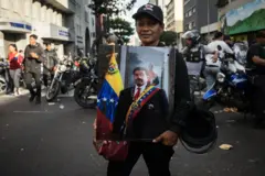 Uma pessoa segura uma imagem de Maduro