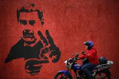 Un motorista pasa junto a un mural con la imagen de Nicolás Maduro.