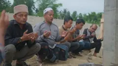 Tokoh yang disegani di Desa Bili Aron, Teungku Faisal (kopiah putih) bersama warga berdoa di dekat monumen Rumoh Geudong, pada Selasa, 26 Maret 2024.