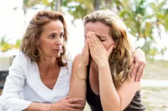 Una mujer abraza a otra que llora.