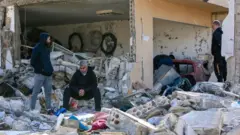 رجلان من قرية بنت جبيل جنوب لبنان أمام حطام منزل تعرض لغارة إسرائيلية منزلهما بعد تعرضه للقصغ