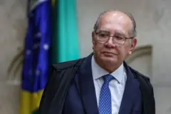 Gilmar Mendes usando toga. Há uma bandeira do Brasil atrás dele.