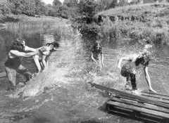 Foto em preto e branco mostrando membros do Black Sabbath jogando água uns nos outros em rio no Wye Valley, em 1977