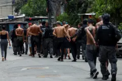 Fila de pessoas presas ao lado da polícia