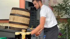 たるから黒ビールをグラスに注ぐ男性