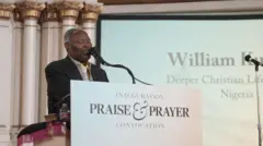 William Kumuyi standing at a pulplit reading 'inauguration praise and prayer convocation'.