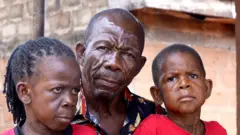 Arakunrin Akwuo ati awọn ọmọ rẹ meji, Chiadi ati Chizaram, joko 