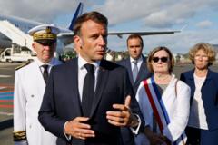 El presidente Macron habla en el aeropuerto de Numea, con autoridades locales detrás.