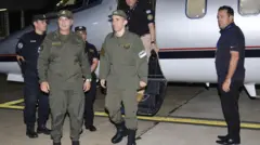 Nahuel Gallo (centro), vestido con su uniforme color verde militar, bajando del avión privado. A su lado ahy 