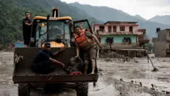 Неколико људи на трактору пролази кроз бујицу воде и блата