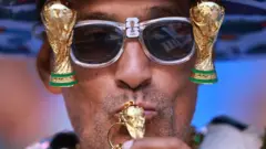Fan con lentes de copas del Mundo besa una copa del Mundo en llavero