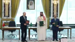 Cumhurbaşkanı Erdoğan, Muhammed bin Selman ve Şahbaz Şerif ayakta ellerindeki anlaşma ile poz veriyor